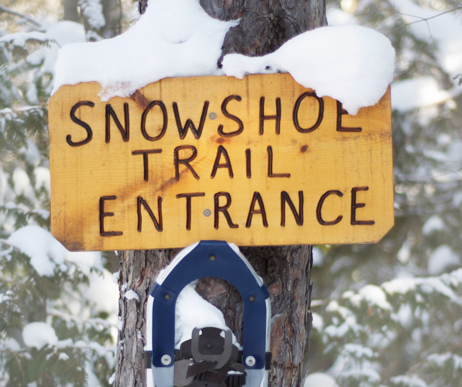 Sign on a snowy tree that says "Snowshoe Trail entrance"